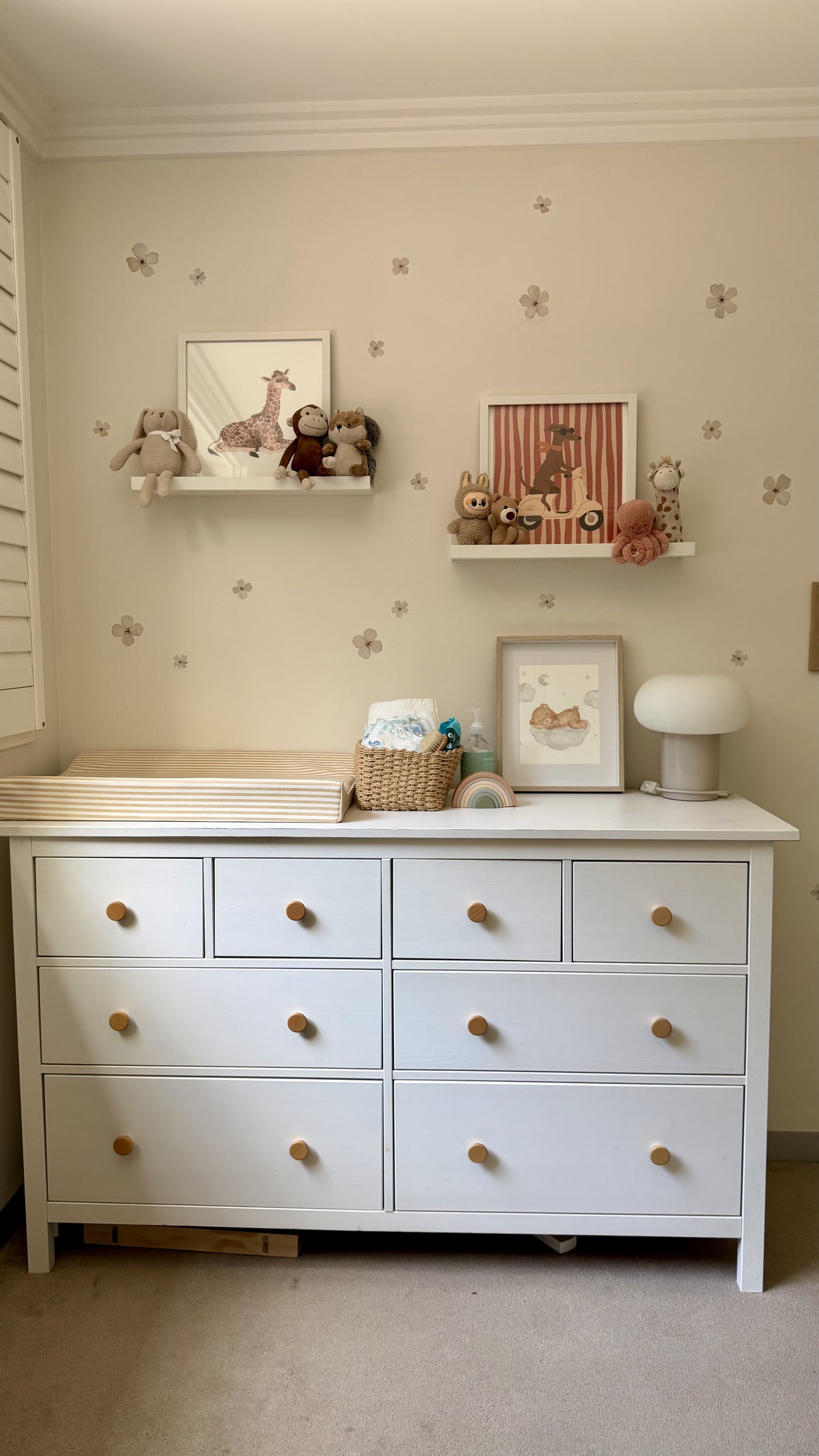 Ivory Bloom floral wall decals decorating a neutral nursery above a white changing table, with soft beige flowers and wooden nursery accessories.